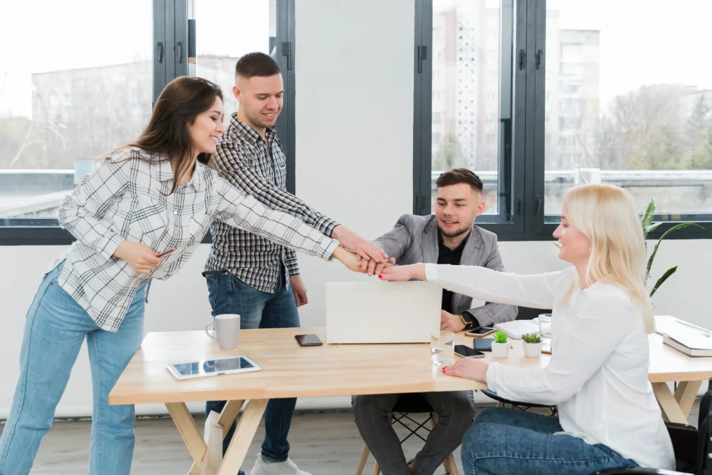 woman-putting-her-hand-together-with-colleagues-scaled